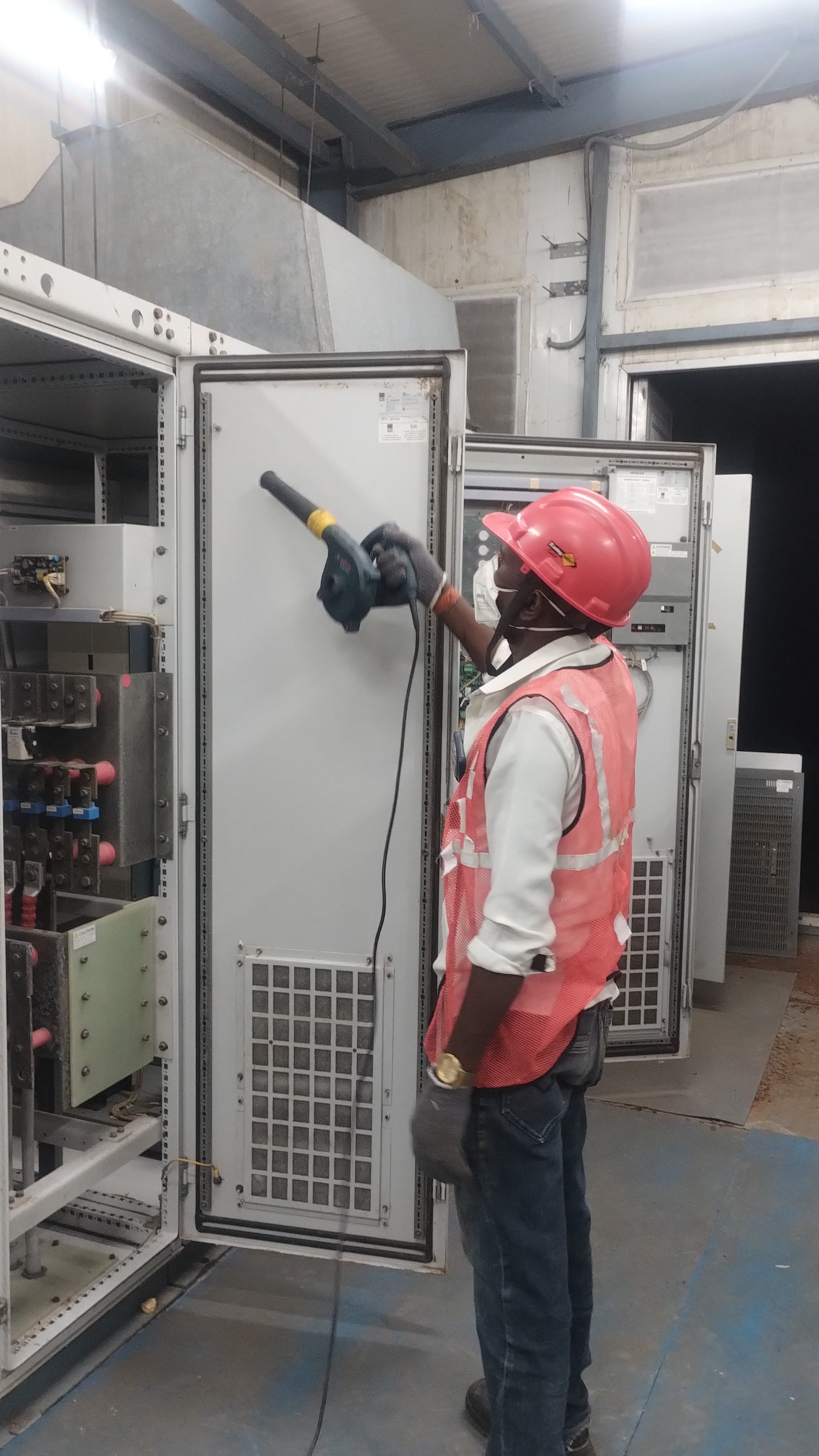 Technician cleaning industrial switchgear and electrical cabinet