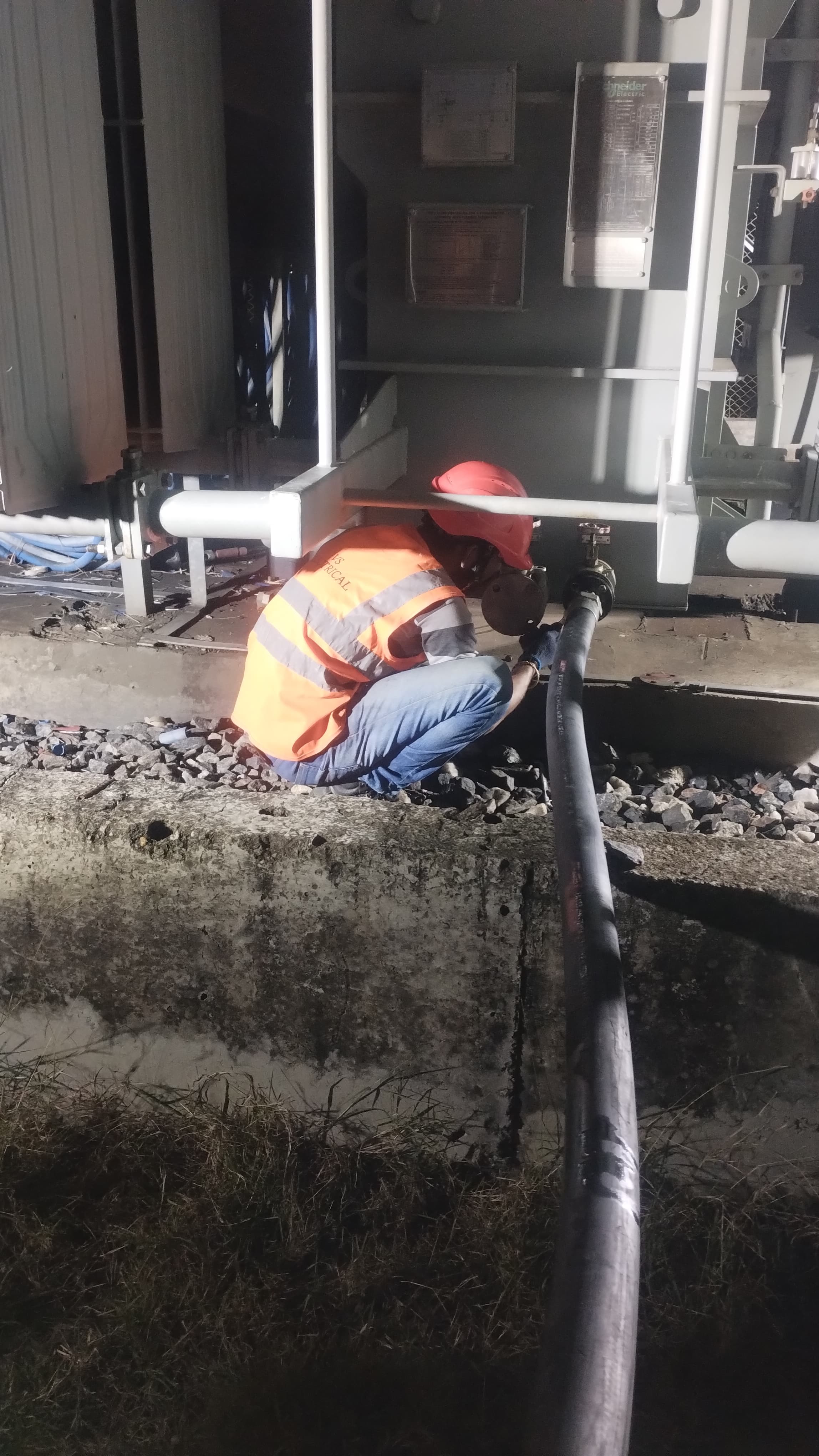 Electrical technician working on transformer cable connection at night