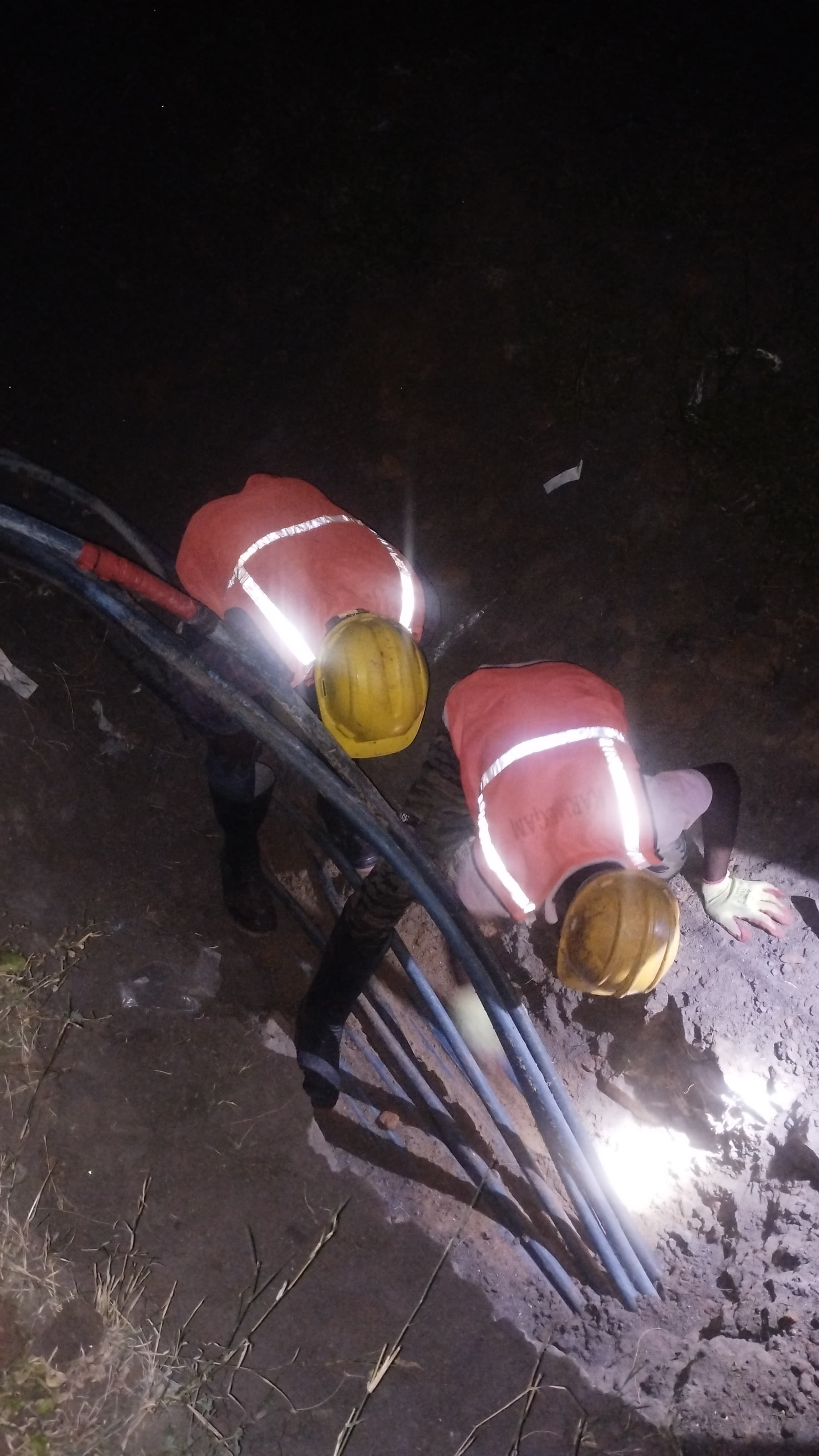 Workers laying underground HT LT cables in trench at night